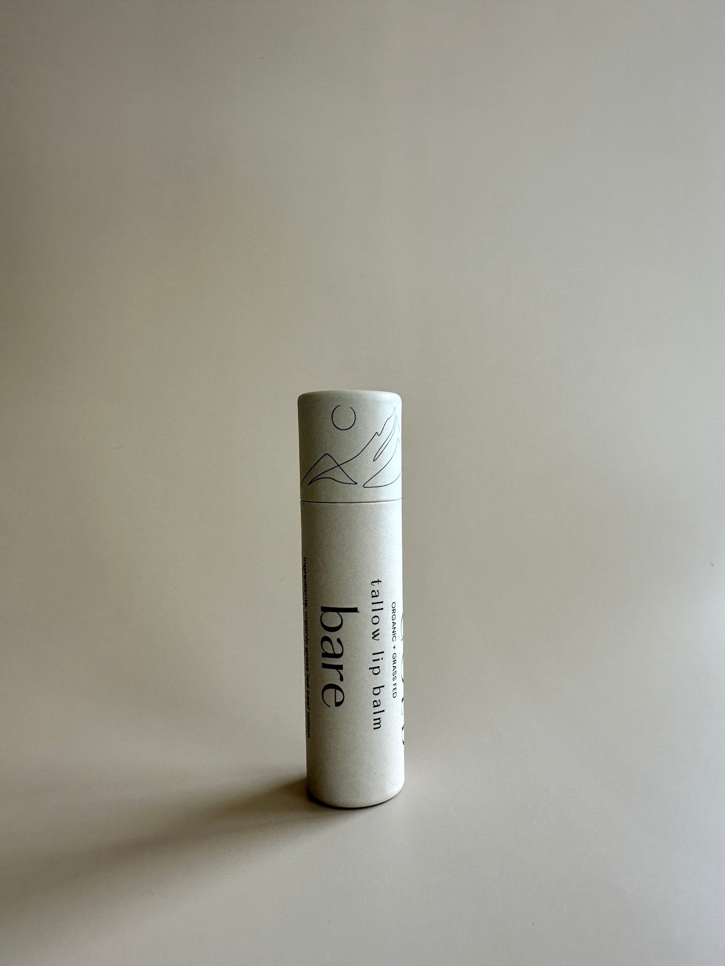 Cardboard tube containing organic tallow lip balm unscented on a neutral background.