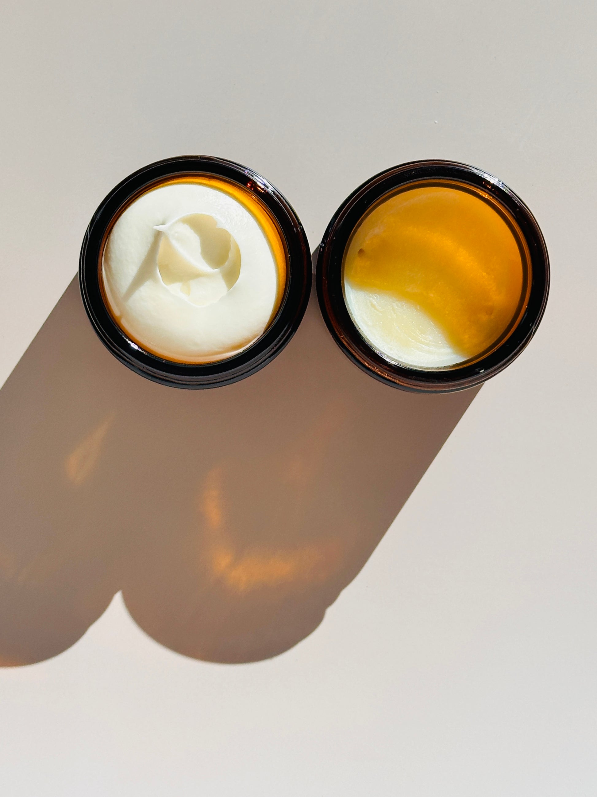Two open containers of cream on a neutral background